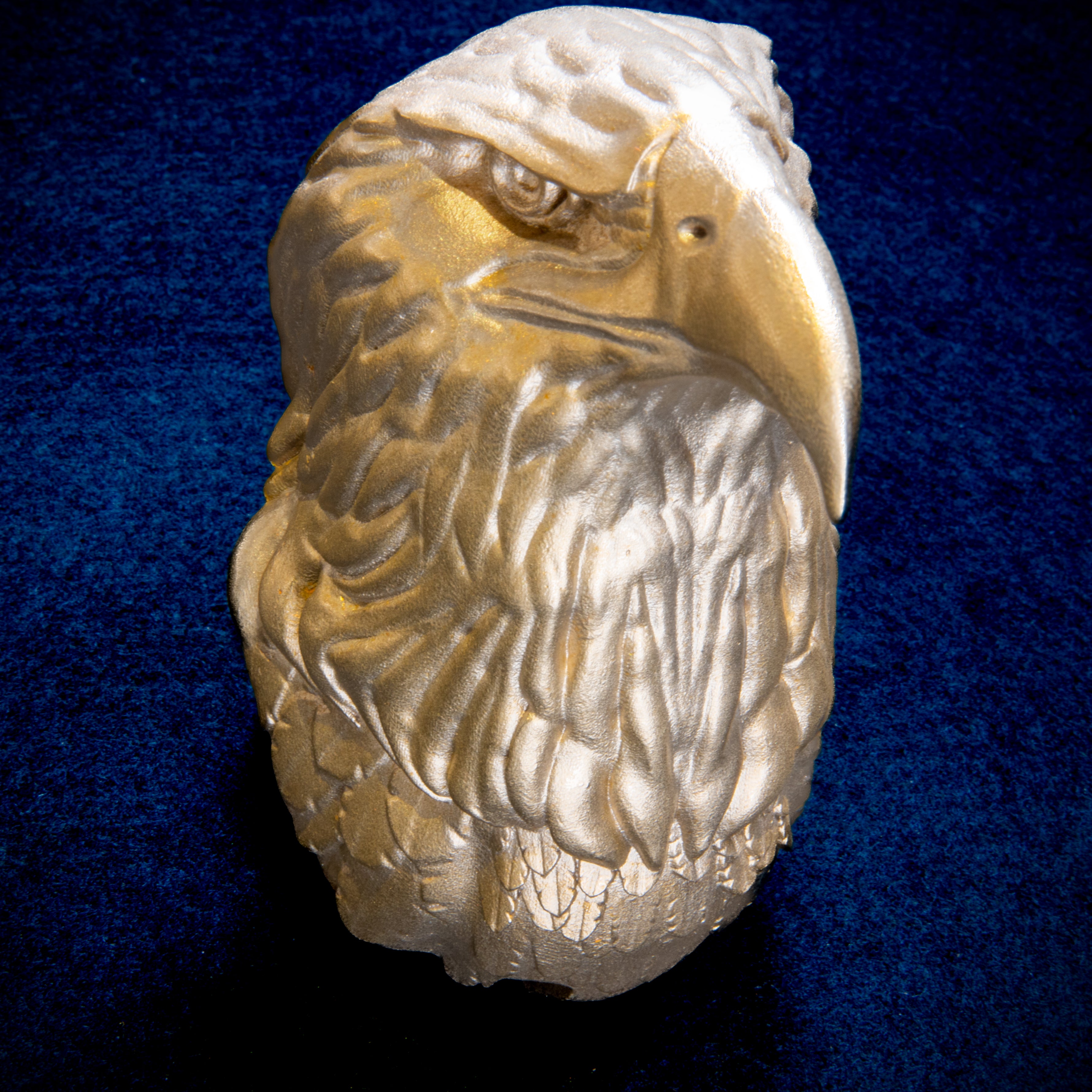 Birds collection: Bald Eagle door knocker head on navy cloth, turned to the right, hooked beak above layers of neck feathers