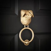 Gloucestershire Old Spot brass door knocker on a black front door, angled view