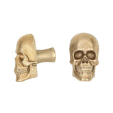 Skull brass cabinet knob and coat hook, cut out on white, one in profile showing the stem, one front on with open eye sockets