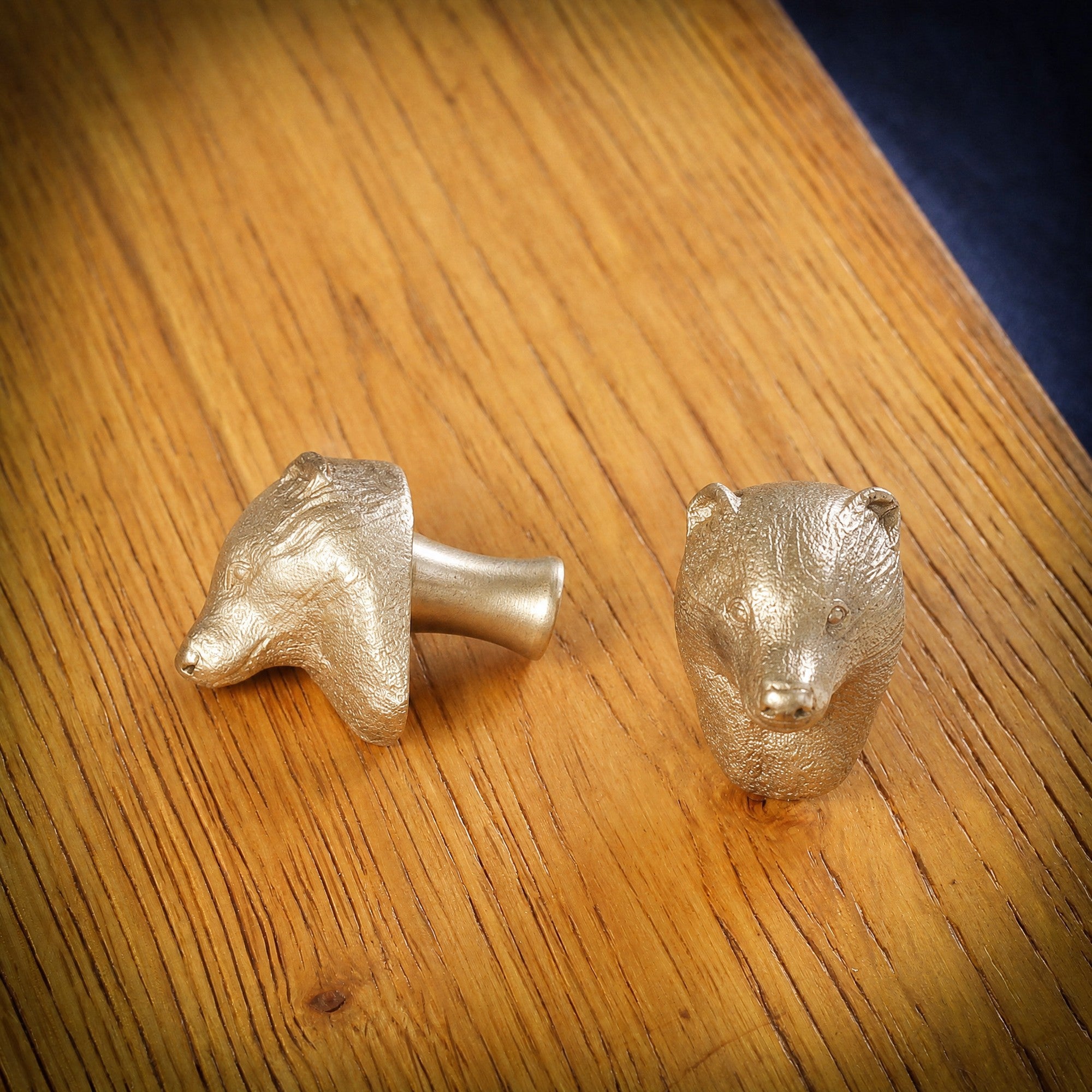 Badger brass cabinet knob and coat hook on an oak board, one on its side showing the stem, one facing front