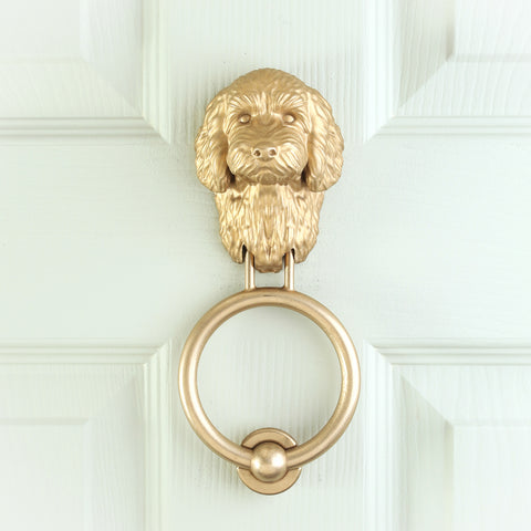 Cockapoo brass door knocker fitted to a pale front door, straight on