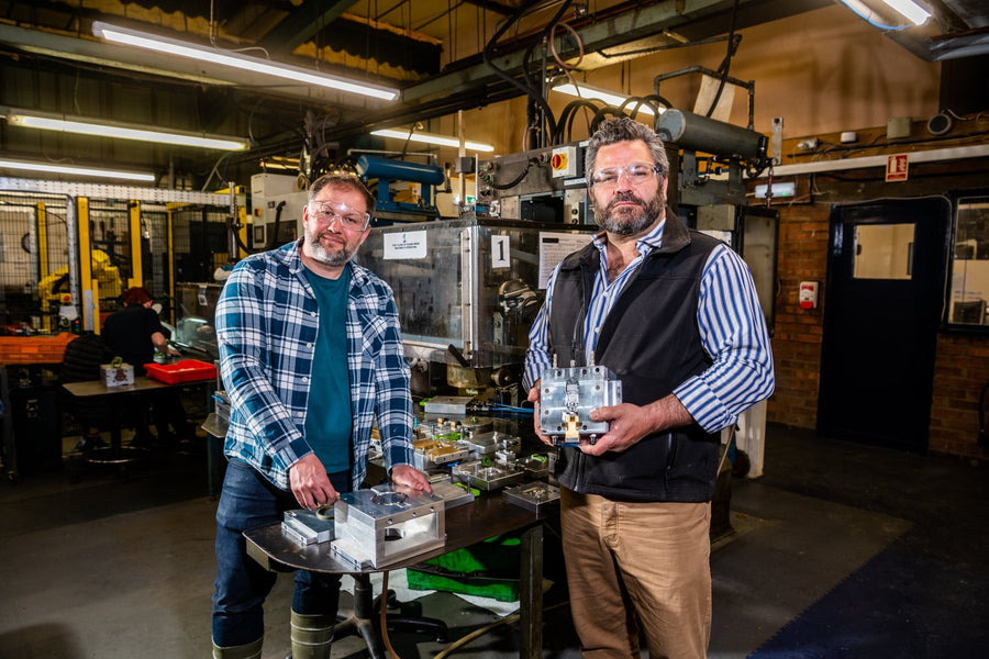 Rob Bennett and Ben Shaw, the two co-founders, standing side by side in a workshop in safety glasses, one holding a machined metal mould block.