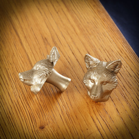 Fox brass cabinet knob and coat hook on an oak board, one on its side showing the stem, one facing front