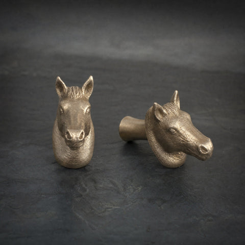 Horse brass cabinet knob and coat hook on dark slate, one facing front, one turned side on showing the stem