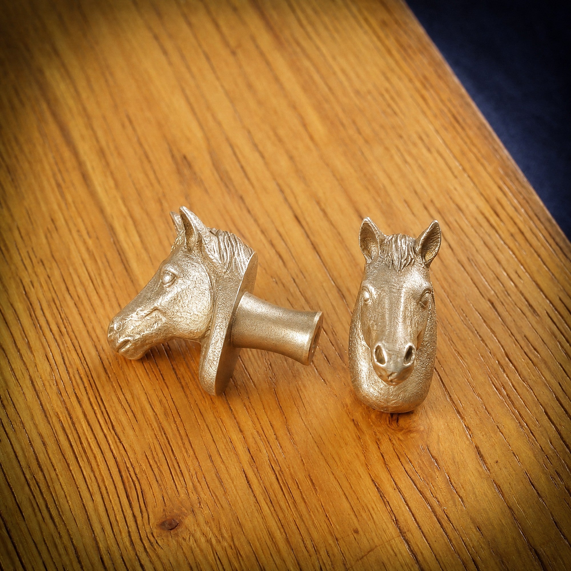 Horse brass cabinet knob and coat hook on an oak board, one on its side showing the stem, one facing front