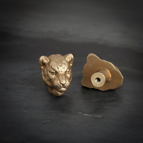 Leopard brass cabinet knob and coat hook on dark slate, one facing front, one turned to show the threaded back