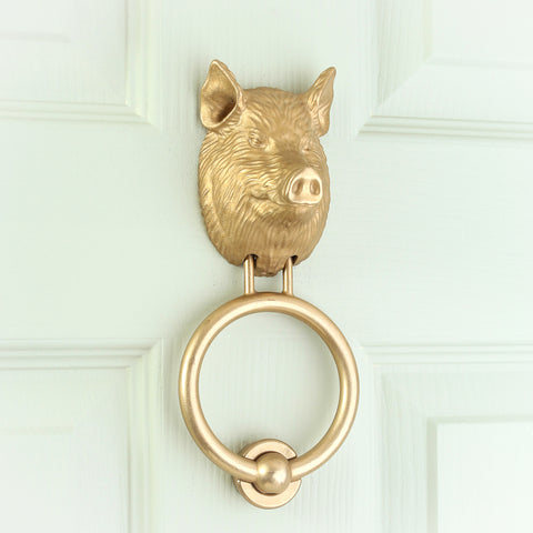 Yorkshire Pig brass door knocker on a pale front door, angled view